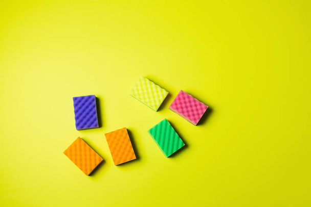 top view of colorful sponges on bright yellow background with copy space - Foto, Imagem