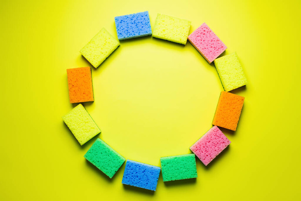 top view of circle frame made of multicolored sponges on yellow background - Фото, зображення