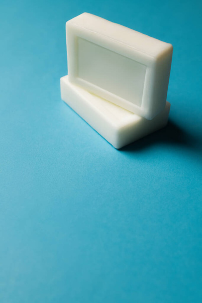 two white soap bars on blue background - 写真・画像