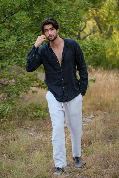 handsome Italian dark-haired guy with shirt in the dry grass. High quality photo - Foto, Imagem