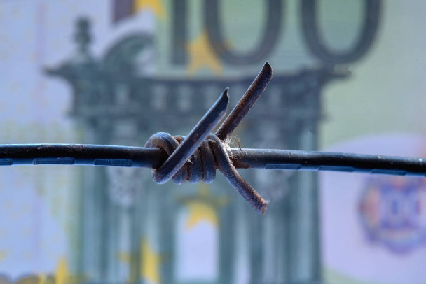Economic warfare, sanctions and embargo busting concept. Close up dirty barbed wire against money of European Union. Horizontal image. - Fotó, kép