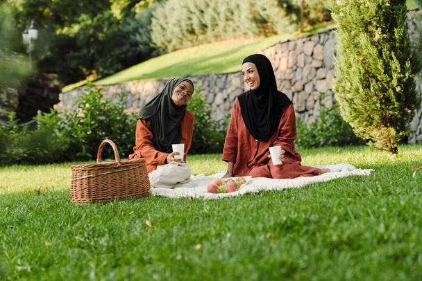 Multiracial muslim women laughing and talking during picnic in green park - Fotoğraf, Görsel
