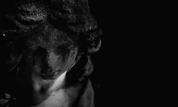 Concepto de muerte. Primer plano antigua estatua de ángel llorando con lágrimas en la cara como símbolo del final de la vida humana. Imagen en blanco y negro. Copiar espacio. - Foto, Imagen