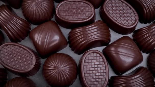 Dark chocolate assorted pralines on black background. Loving chocolate and sweets concept. Dolly shot 4k - Video