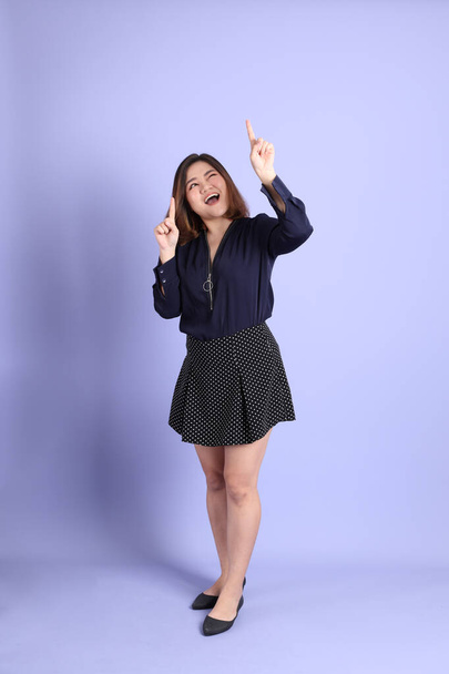 The chubby Asian woman standing on the purple background with the casual clothes. - Foto, immagini