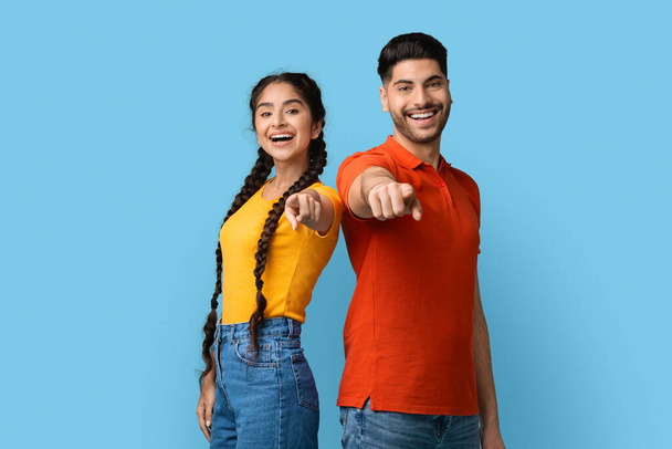 Positive young middle eastern man and woman pointing with fingers at camera - Photo, Image