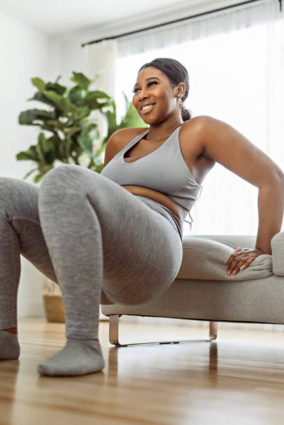 Una mujer afroamericana haciendo ejercicio en casa sala de estar gimnasio - Foto, imagen