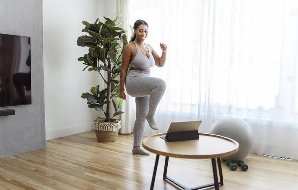 An African american woman working out in home livingroom gym - Fotó, kép