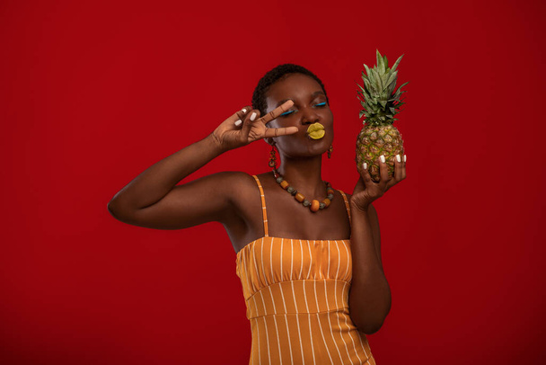 Emotional black lady fashionista with pineapple on red - Foto, Imagem