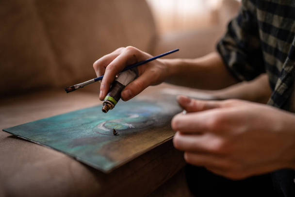 Gros plan sur les mains d'une femme artiste caucasienne inconnue ou peinture fille sur toile à l'aide de pinceau et de couleurs pour rendre l'art professionnel ou passe-temps - Photo, image