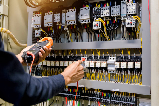 Testeur de travail ingénieur électricien mesurant la tension et le courant de la ligne électrique dans le contrôle de l'armoire électrique. - Photo, image