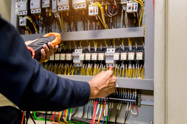 Probador de trabajo de ingeniero eléctrico que mide el voltaje y la corriente de la línea eléctrica de energía en el control del gabinete electico. - Foto, imagen