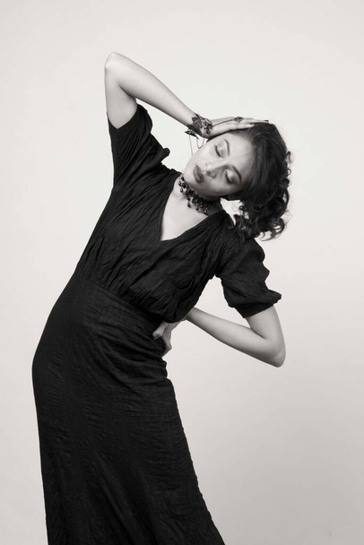 красива жіноча модель в модному чорному платті перед міцним тлом в студії
 - Фото, зображення
