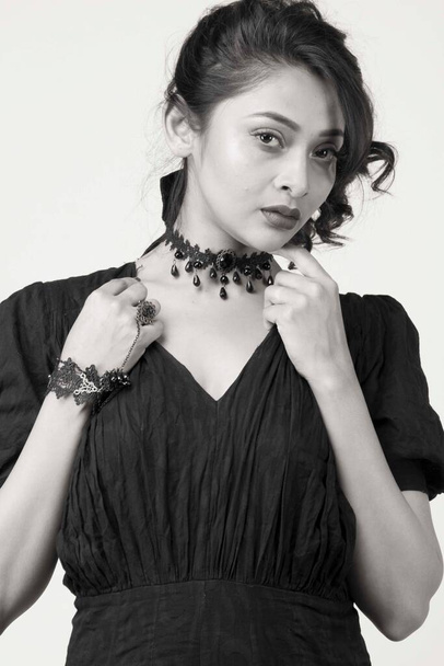 mooi vrouwelijk model in modieuze zwarte jurk voor een solide achtergrond in een studio - Foto, afbeelding