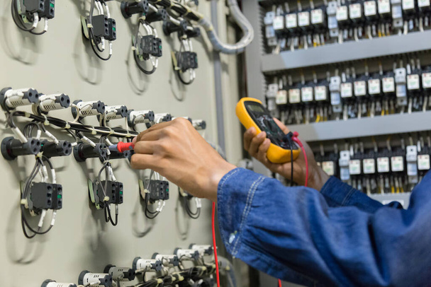 Elektricien ingenieur werk tester meetspanning en stroom van de macht elektrische lijn in electische kast controle. - Foto, afbeelding
