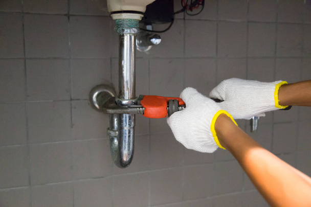 Loodgieter bevestiging witte gootsteen pijp met verstelbare moersleutel . - Foto, afbeelding