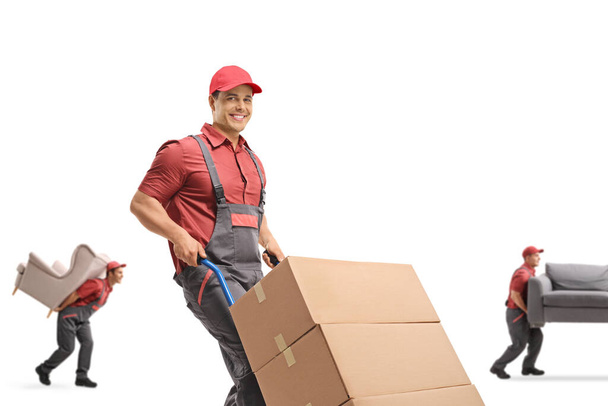 Mover pushing a hand-truck and other workers carrying furniture isolated on white background - Foto, Imagem