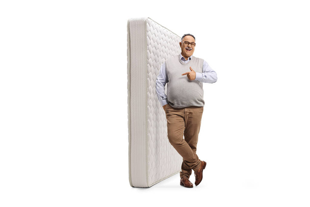Mature man leaning on a bed mattress isolated on white background - Φωτογραφία, εικόνα