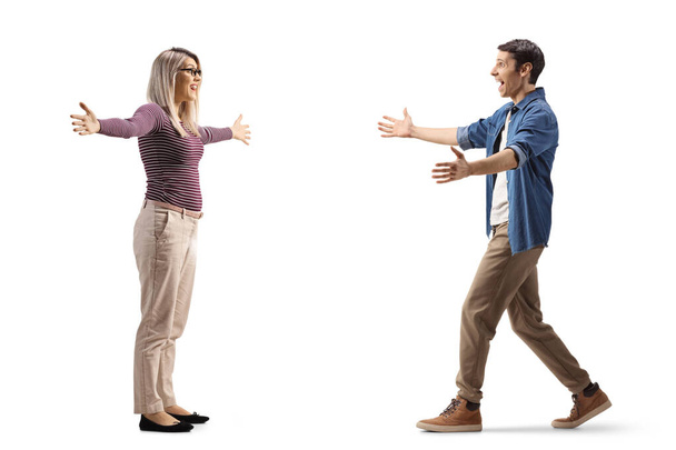 Full length profile shot of a young man and woman meeting each other with open arms isolated on white background - Foto, immagini