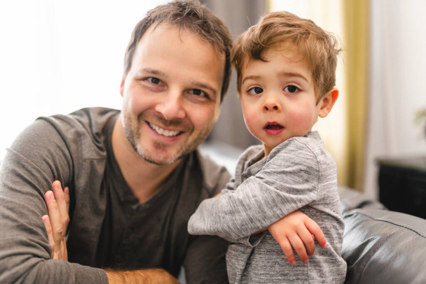 Portrait of little boy with father having fun on sofa with attitude - Foto, Imagen