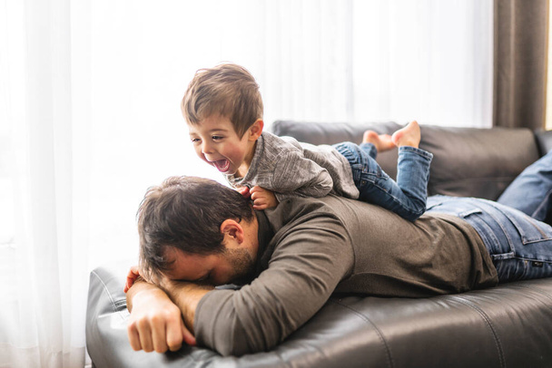 Tired young father with boy on back a concept of hyperactive children and tired parents - 写真・画像