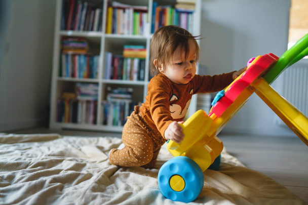 Küçük beyaz bir bebek, altı ya da yedi aylık. Evde, odada oyuncaklarla oynuyor. Bebek, yeni oyuncakları incelerken eğleniyor. - Fotoğraf, Görsel