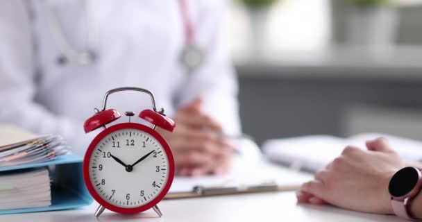 Doctor communicates with patient of clinic on table is alarm clock - Séquence, vidéo