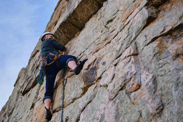 Hombre adulto concentrado escalando una pared de roca - Foto, Imagen