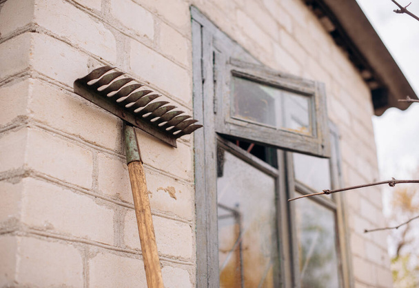 Minimalist image of old rake hanging on brick wall - Fotó, kép