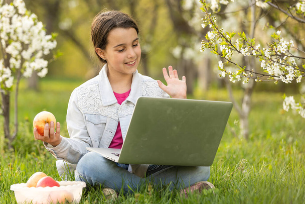 Mała dziewczynka używająca laptopa na podwórku. Dziecko uczące się w domu odrabia lekcje lub ma lekcje online. Koncepcja nauczania w domu. - Zdjęcie, obraz