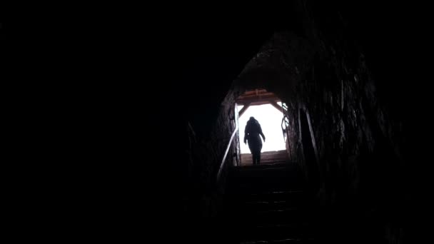 Una mujer camina a través de un largo túnel oscuro. La cámara se acerca.. - Imágenes, Vídeo