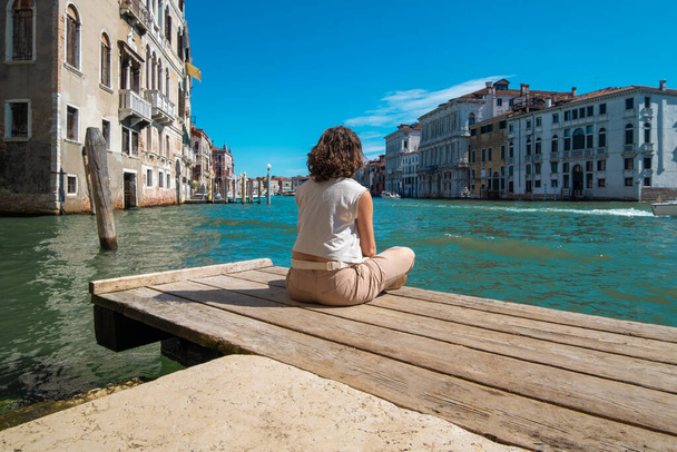 Νεαρή γυναίκα διαλογίζεται αντικρίζοντας τα κανάλια της Βενετίας στην Ιταλία. - Φωτογραφία, εικόνα
