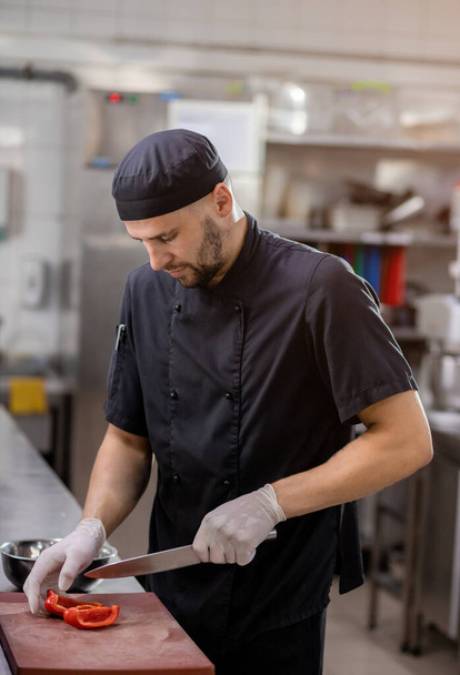 Кухар вирізає болгарський перець на дошці для гриля
 - Фото, зображення