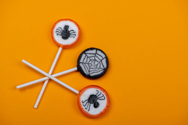 Siyah örümcekli Cadılar Bayramı şekeri ve turuncu arka planda örümcek ağı, üst görünüm - Fotoğraf, Görsel