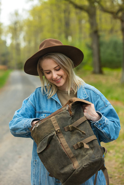 Smiling woman check backpack on road in forest  - Фото, зображення