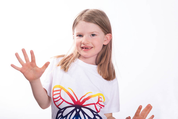 attraente sorridente bambina senza denti davanti, t-shirt bianca con una farfalla su uno sfondo bianco studio  - Foto, immagini