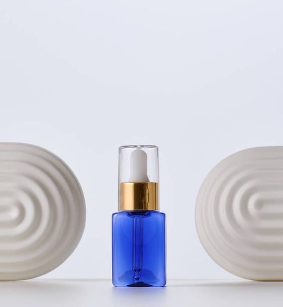 μπλε γυάλινο μπουκάλι με πιπέττα για καλλυντικά, έλαια και ορό. Διαφήμιση και προώθηση προϊόντων - Φωτογραφία, εικόνα