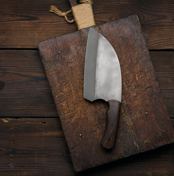 Large kitchen knife on an empty wooden cutting board, top view - Fotó, kép