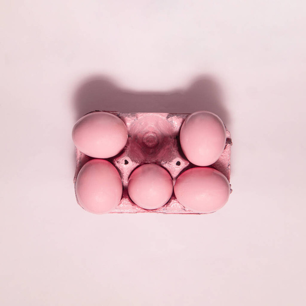 Monochromatic pastel eggs in carton on light pink background. Minimalistic Easter concept. Creative holiday idea. - Photo, image