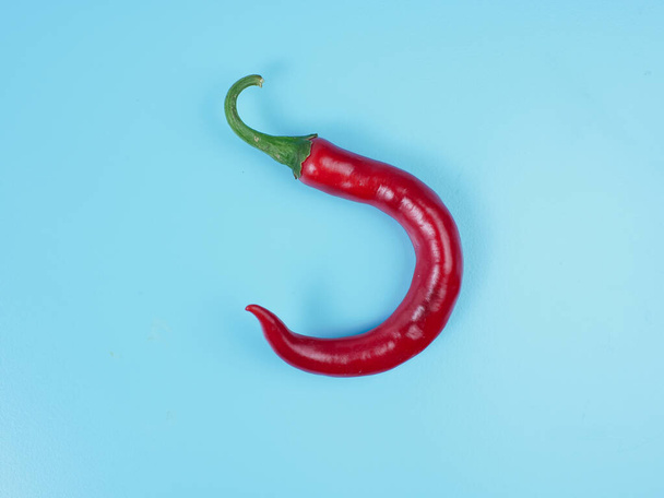 Chili peppers isolated on blue background. Red hot chili peppers as an ingredient of Asian and Mexican cuisine and spices - Фото, изображение