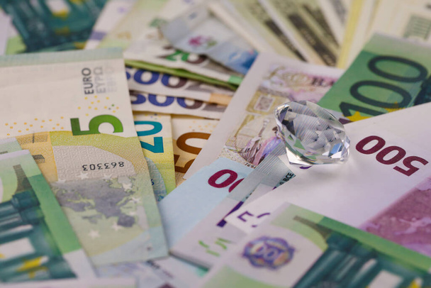 Euro ja dollari rahaa laskut ja kolikot suuri timantti lähikuva. Suuri määrä rahaa ja valtava läpinäkyvä helmi pöydällä. Liiketoiminnan ja korujen käsite - Valokuva, kuva
