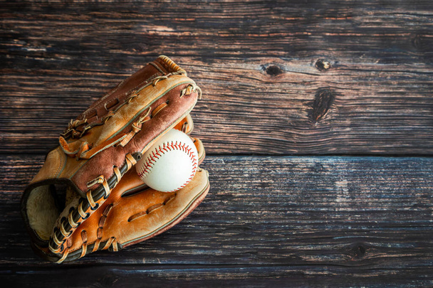 Skórzana rękawica baseballowa lub softball z piłką na rustykalnym drewnianym tle z przestrzenią do kopiowania. - Zdjęcie, obraz