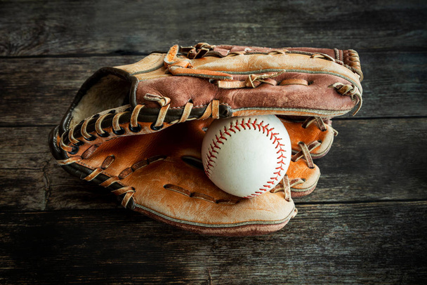 Шкіряний бейсбол або софтбол рукавички з м'ячем на сільському дерев'яному фоні
. - Фото, зображення