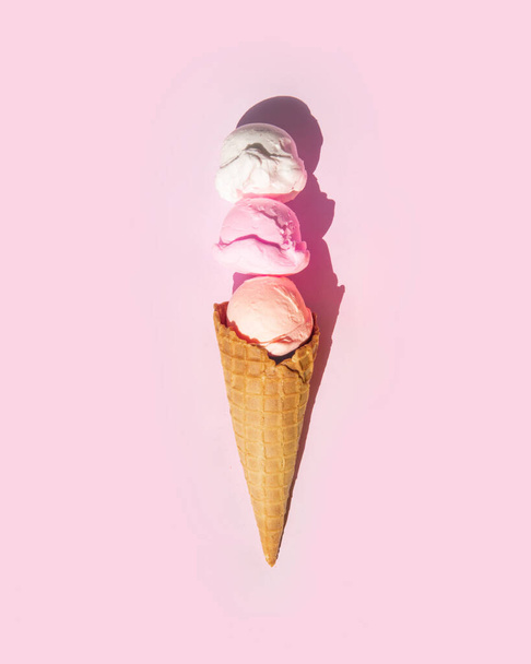 Pastel light ice cream balls in cone on light pastel pink background. Creative food concept. Minimalistic sweets composition. Sunny summer idea. - Photo, image