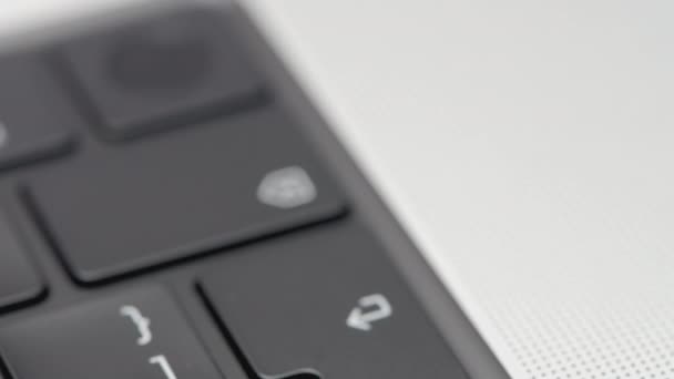Parte della tastiera nera nella cornice. Azione. Tastiera nera in un computer portatile argentato. Angolo con pulsanti sulla tastiera di un computer portatile in argento - Filmati, video