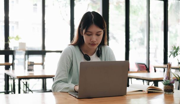 Poważne skupiony student azjatycki za pomocą laptopa w kuchni, patrząc na ekranie z uwagą i koncentracją, oglądanie nauki webinarium, wirtualny trening, kurs wideo, nauka od hom - Zdjęcie, obraz