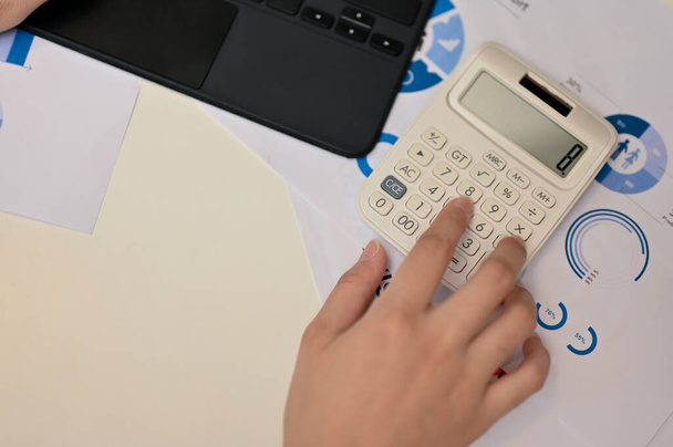 Vue du dessus, Femme tapant à la main sur la calculatrice, utilisant la calculatrice ou calculant son travail financier avec la calculatrice à son bureau. - Photo, image
