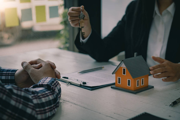 Home Sales en Home Verzekeringen Ideeën Makelaars bieden rentetarieven, bespreken de voorwaarden van het huis koopcontract, en vragen klanten om documenten te ondertekenen om het contract legaal in te voeren. - Foto, afbeelding