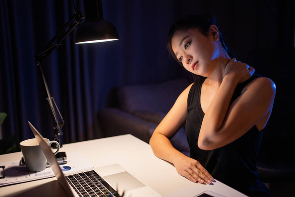 Le donne asiatiche sono stanche. Si massaggiava il collo per allentare i muscoli dal lavorare al computer di notte.. - Foto, immagini