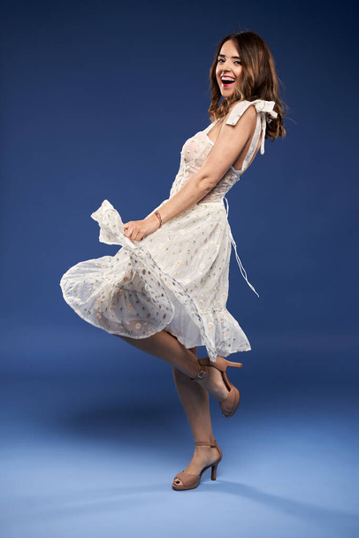 Portrait of a beautiful young woman in white dress on blue background - Zdjęcie, obraz